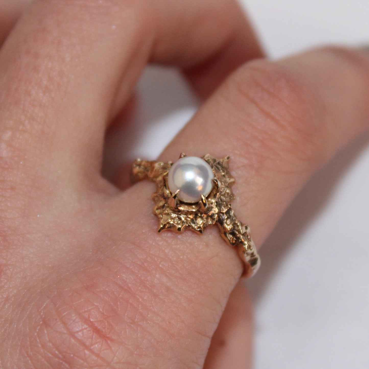 14k yellow gold ring with a 6mm white pearl centerpiece on finger