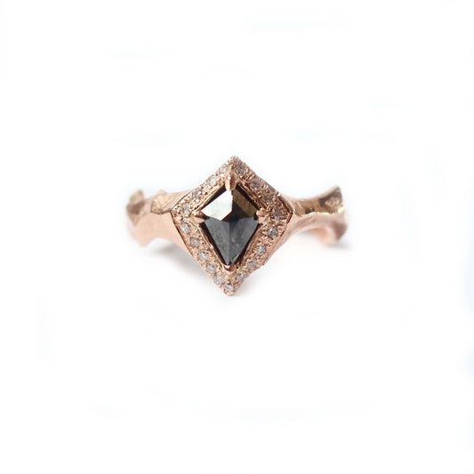 Close-up of a kite shape diamond engagement ring with pavé halo and dark center stone